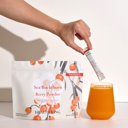 Person adding berry powder to a glass of juice with a package of Sea Buckthorn Berry Powder in the background.
